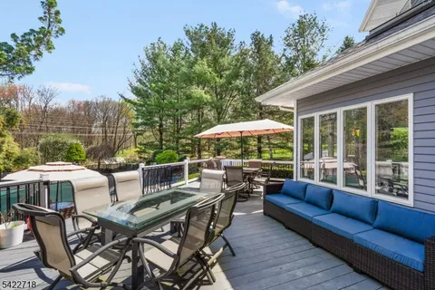 a view of a patio with a dining table and chairs under an umbrella with a small yard