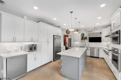a large white kitchen with a stove a sink a refrigerator and a microwave