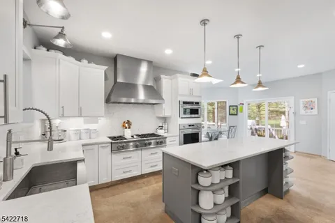 a kitchen with a stove a sink a kitchen island with wooden cabinets and floor