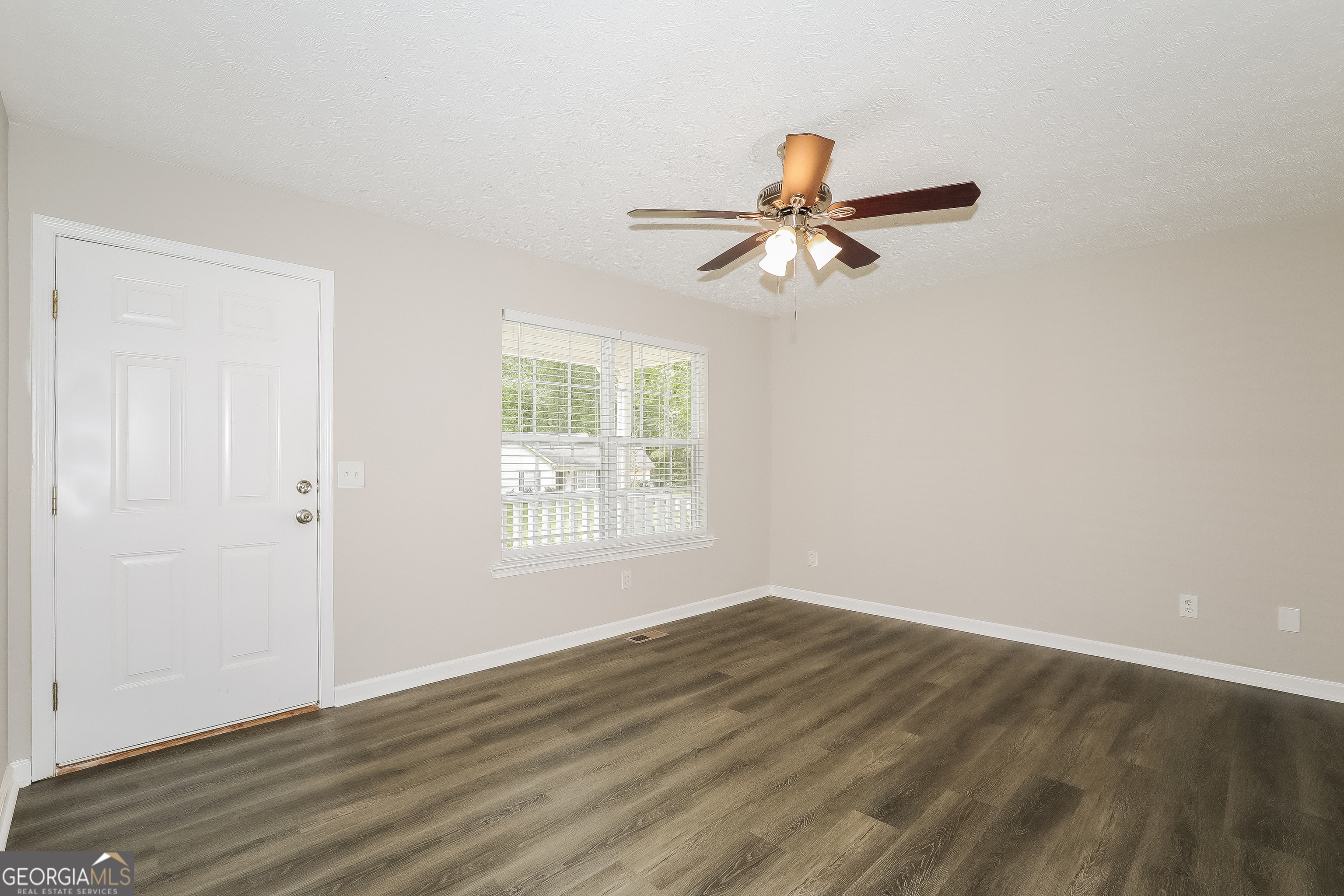6530 River Hill Drive Flowery Branch, GA 30542 - Photo 2 of 14 an empty room with wooden floor fan and windows