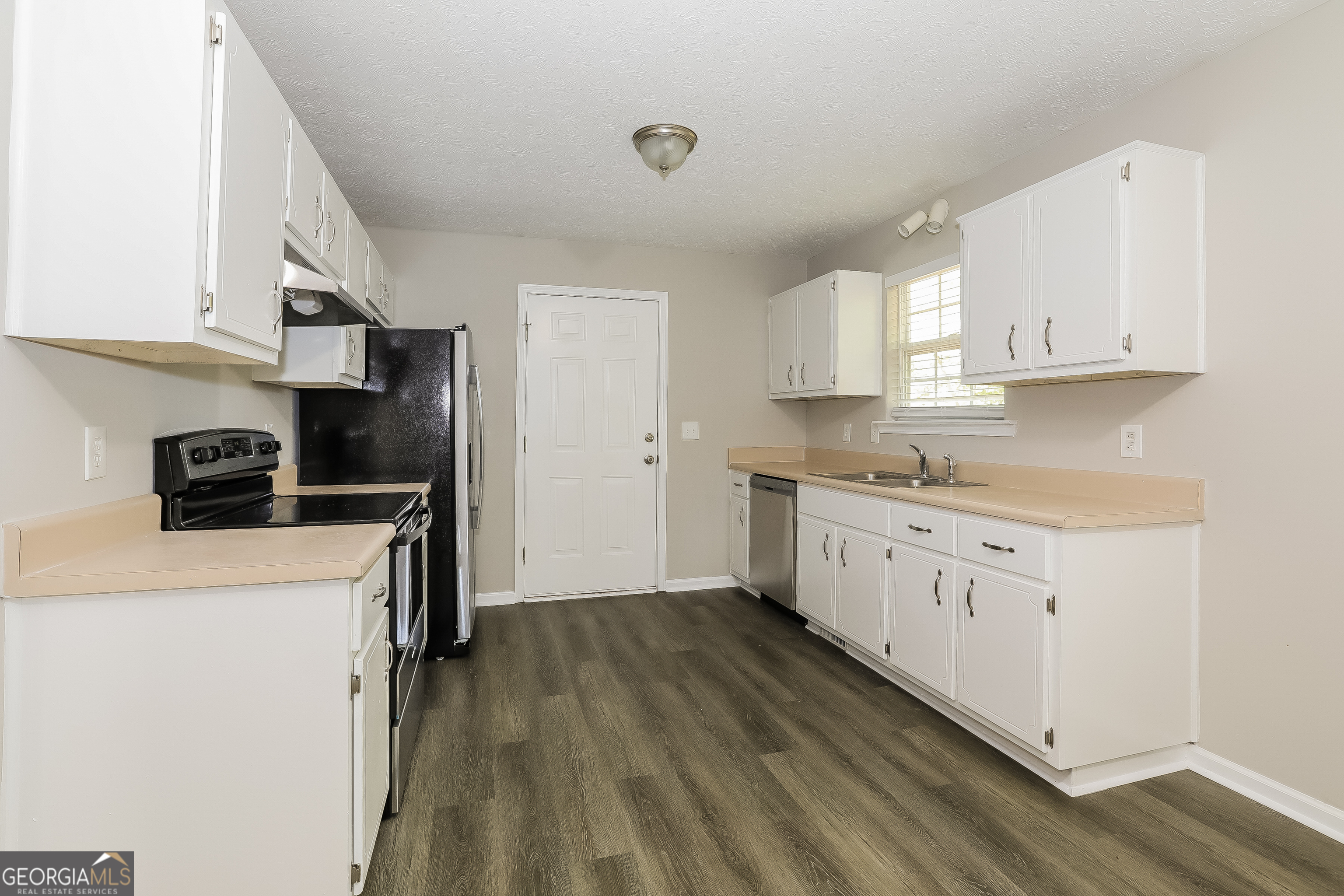 6530 River Hill Drive Flowery Branch, GA 30542 - Photo 4 of 14 a kitchen with a refrigerator a stove top oven and white cabinets