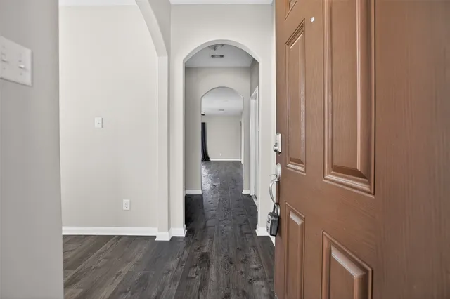 a view of a hallway with wooden floor and a livingroom