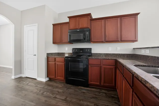 a kitchen with granite countertop wooden cabinets and stainless steel appliances
