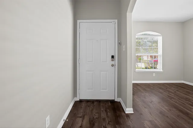 an empty room with wooden floor mirror and windows
