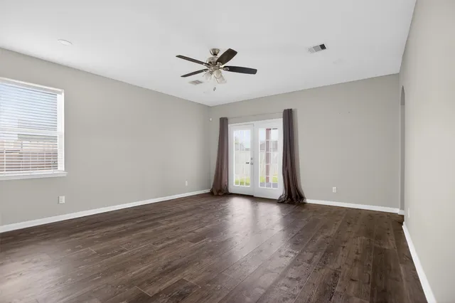 a view of an empty room with wooden floor and a window