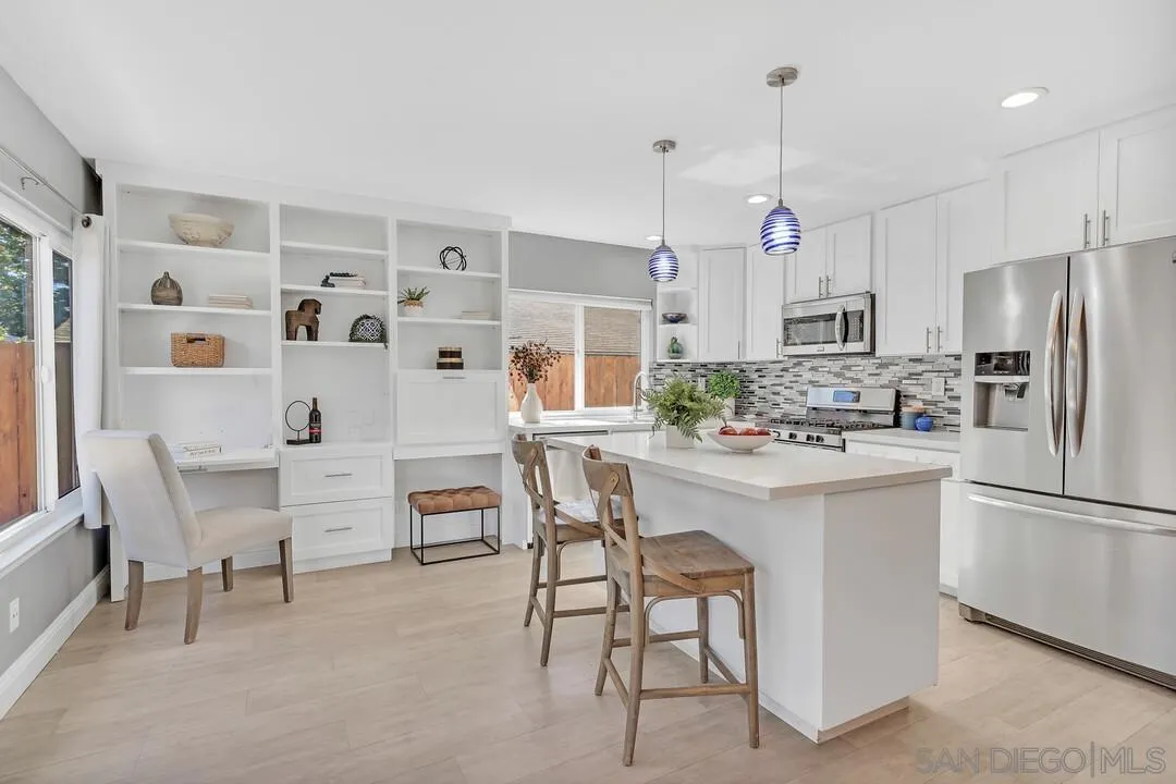 11021 Sagittarius Road San Diego, CA 92126 - Photo 7 of 28 a kitchen with stainless steel appliances kitchen island granite countertop a table chairs and a refrigerator