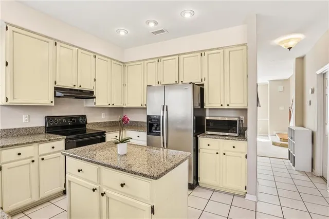 a kitchen with granite countertop a stove sink and refrigerator
