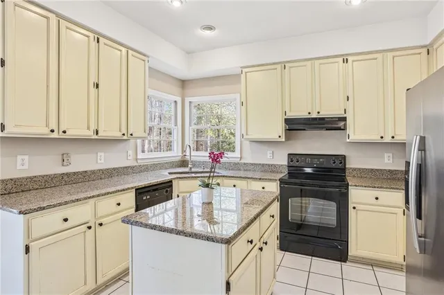 a kitchen with stainless steel appliances granite countertop a sink stove refrigerator and cabinets