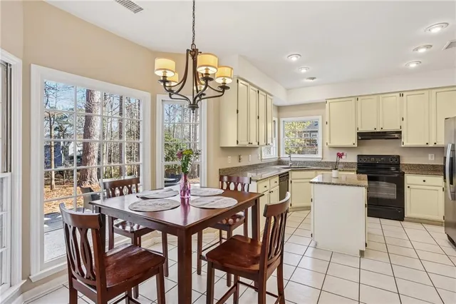 a kitchen with stainless steel appliances granite countertop a stove a refrigerator a kitchen island a table and chairs