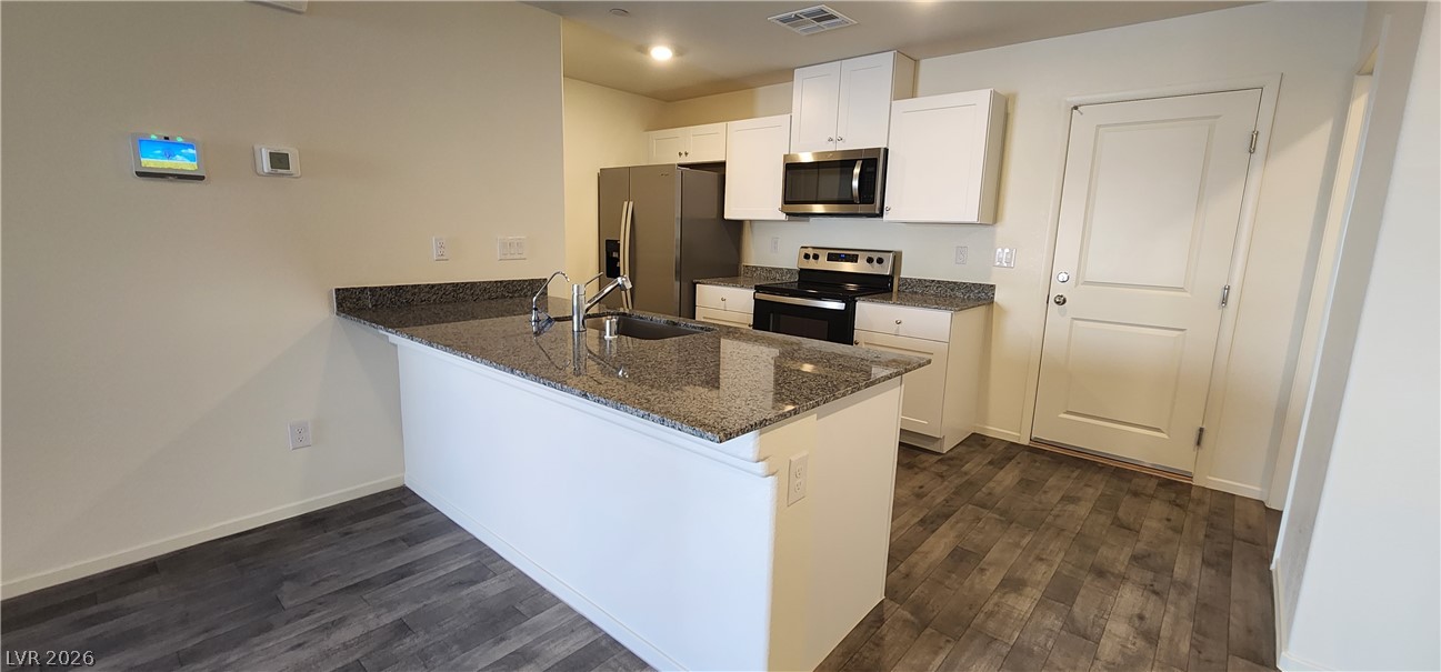 9127 Rory Storm Street Las Vegas, NV 89113 - Photo 4 of 27 Polished granite countertops and seamless wood flooring highlight this functional contemporary kitchen.