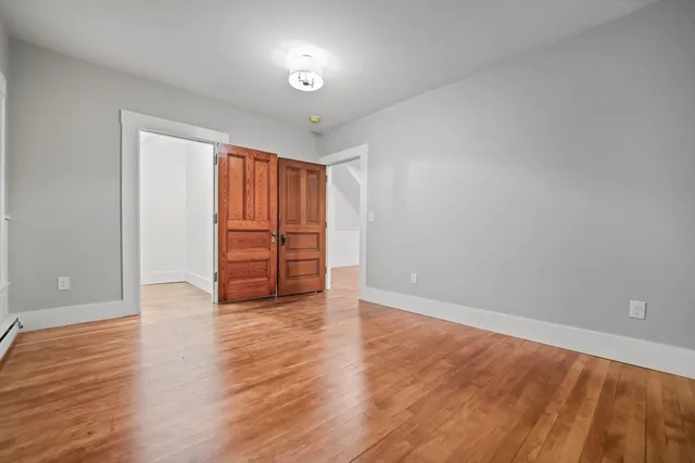 a view of an empty room with wooden floor and closet