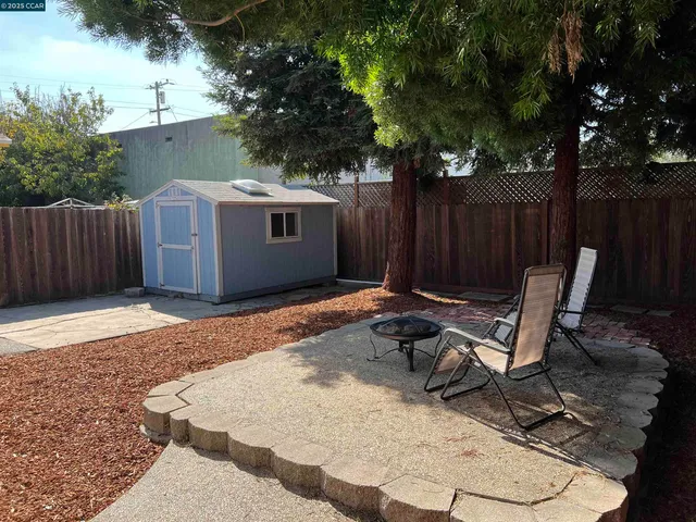a view of backyard with wooden fence and a large tree