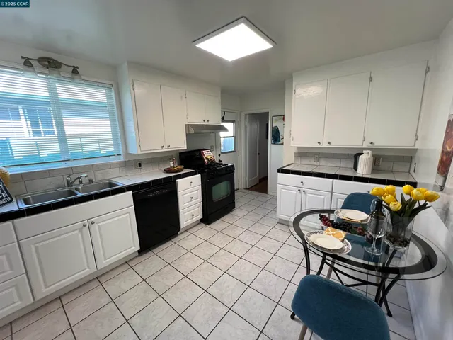 a kitchen with stainless steel appliances granite countertop a sink a stove a refrigerator cabinets and living room view