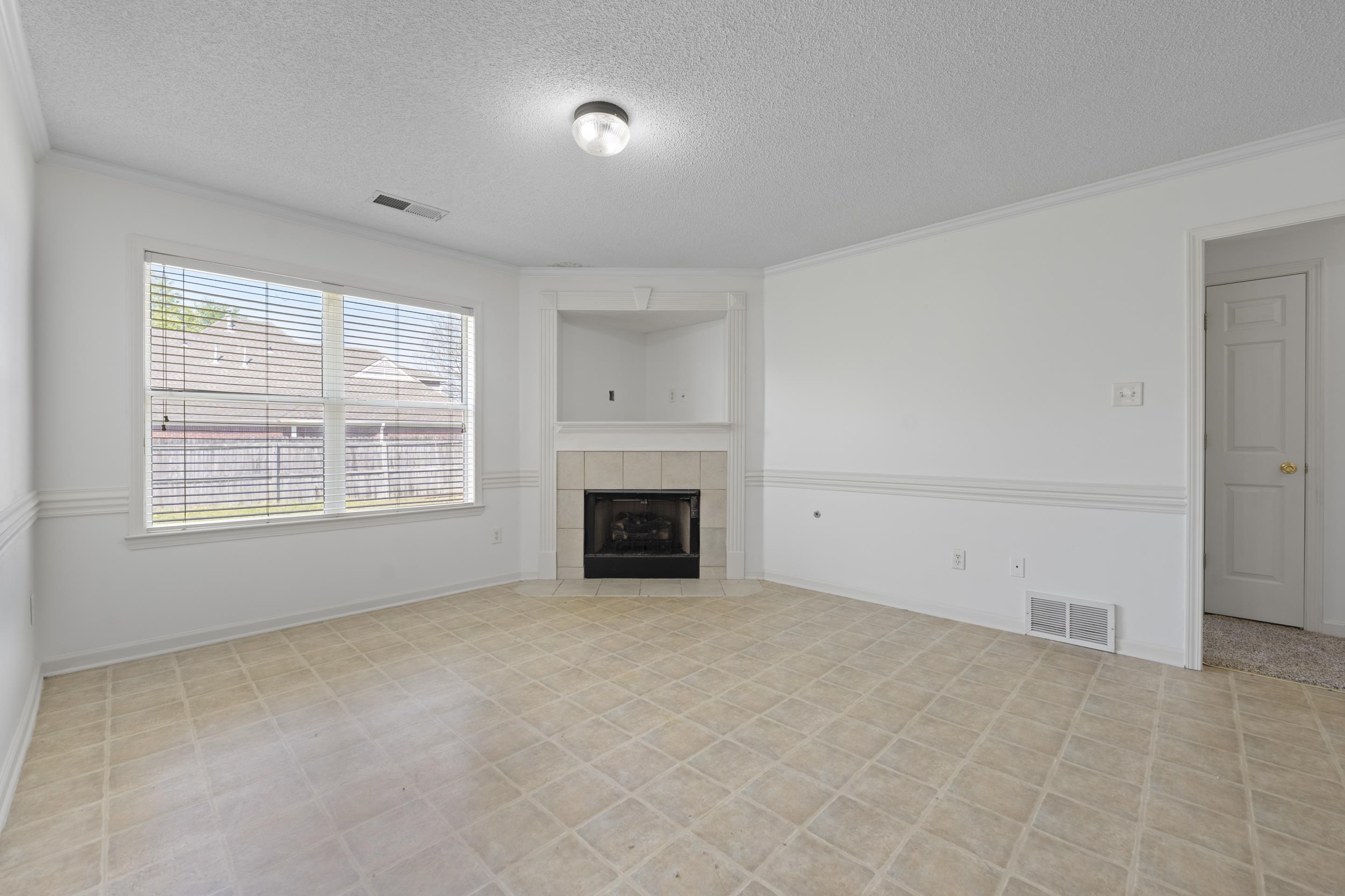 1104 Macon Hall Road Cordova, TN 38018 - Photo 16 of 34 Unfurnished living room with a textured ceiling, a tile fireplace, ornamental molding, and visible vents