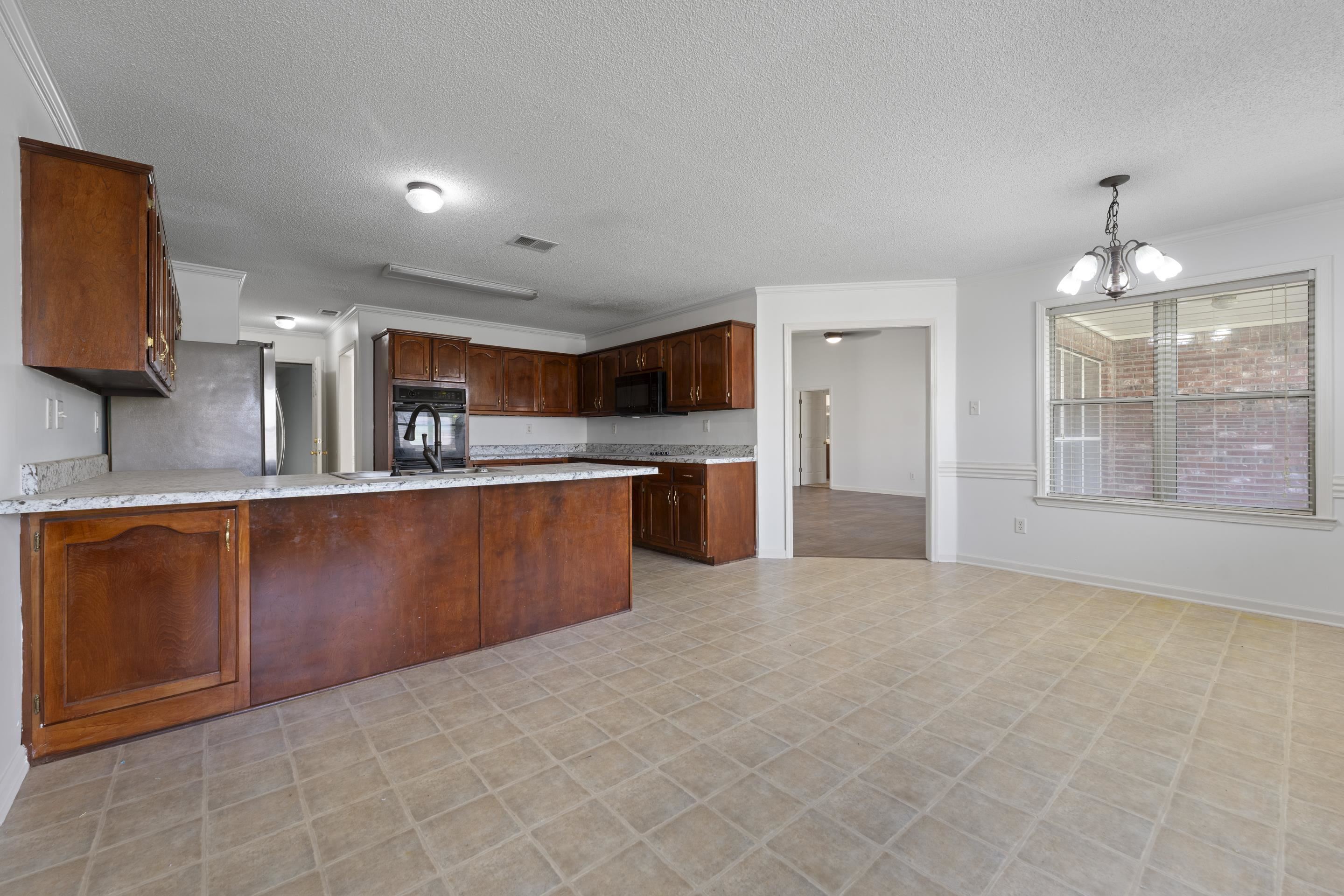 1104 Macon Hall Road Cordova, TN 38018 - Photo 17 of 34 Kitchen featuring an inviting chandelier, a peninsula, a textured ceiling, black appliances, and light floors