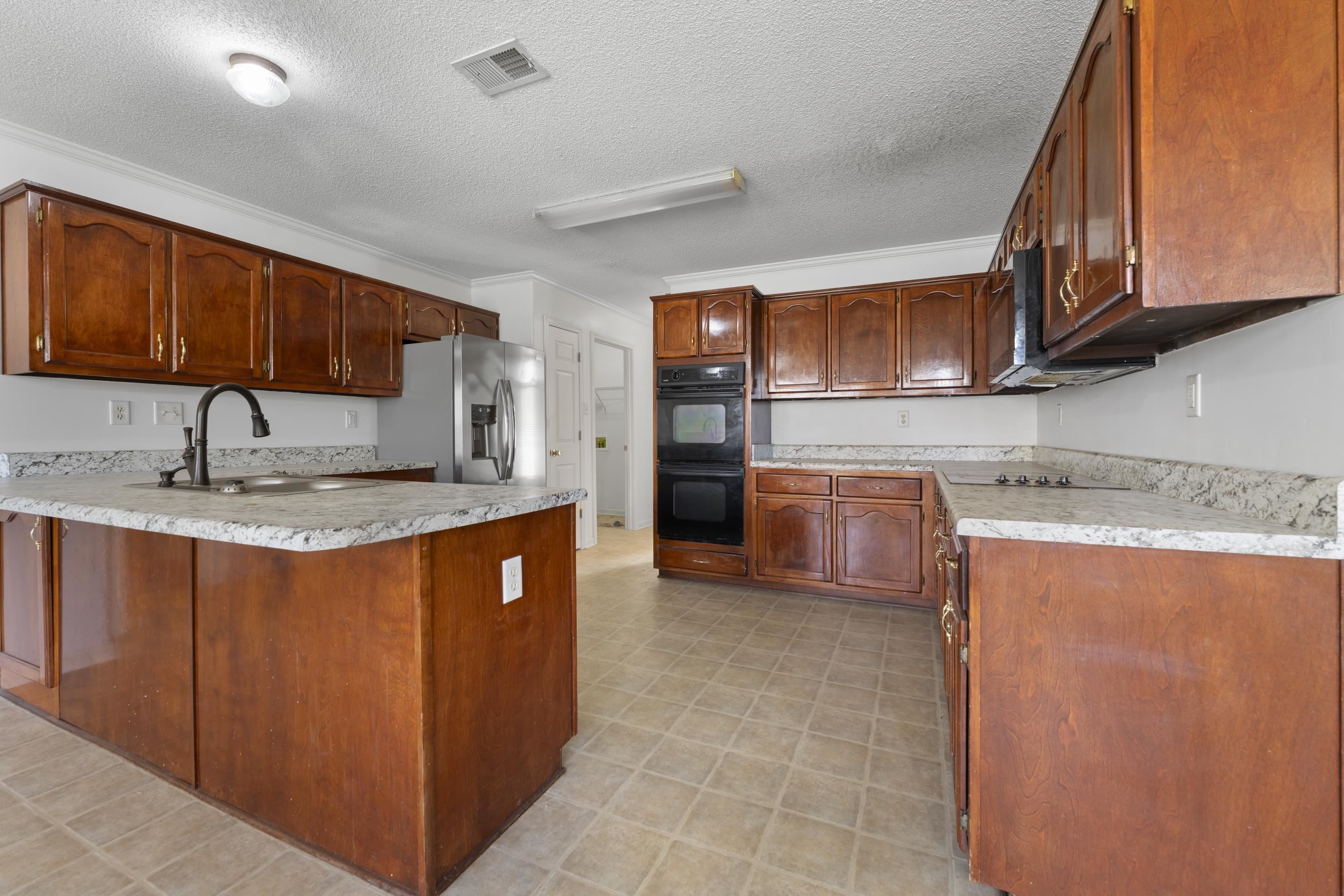 1104 Macon Hall Road Cordova, TN 38018 - Photo 18 of 34 Kitchen with a peninsula, a textured ceiling, visible vents, black appliances, and a sink