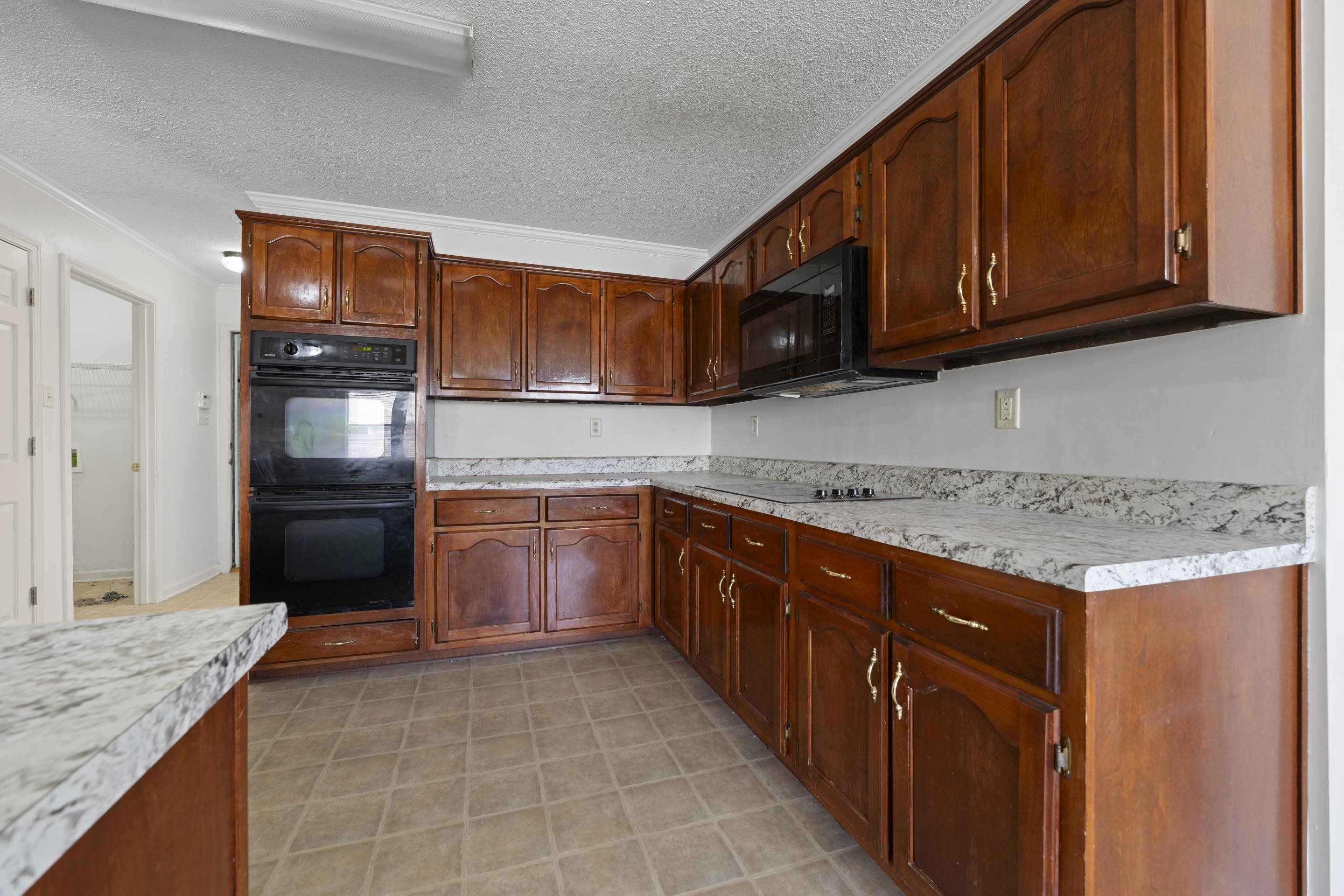1104 Macon Hall Road Cordova, TN 38018 - Photo 19 of 34 Kitchen featuring crown molding, light countertops, black appliances, and a textured ceiling