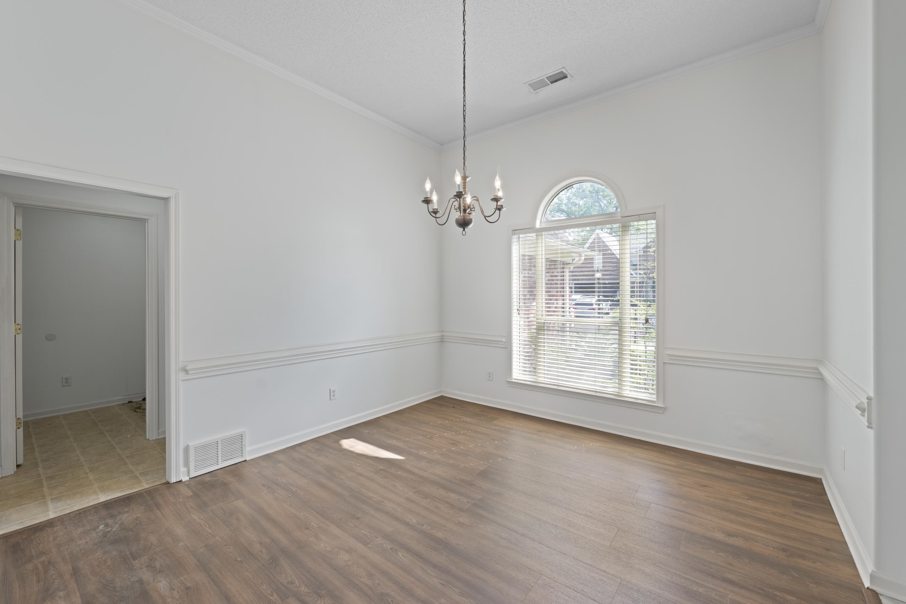 1104 Macon Hall Road Cordova, TN 38018 - Photo 3 of 34 Unfurnished dining area with visible vents, dark wood-style flooring, an inviting chandelier, and ornamental molding