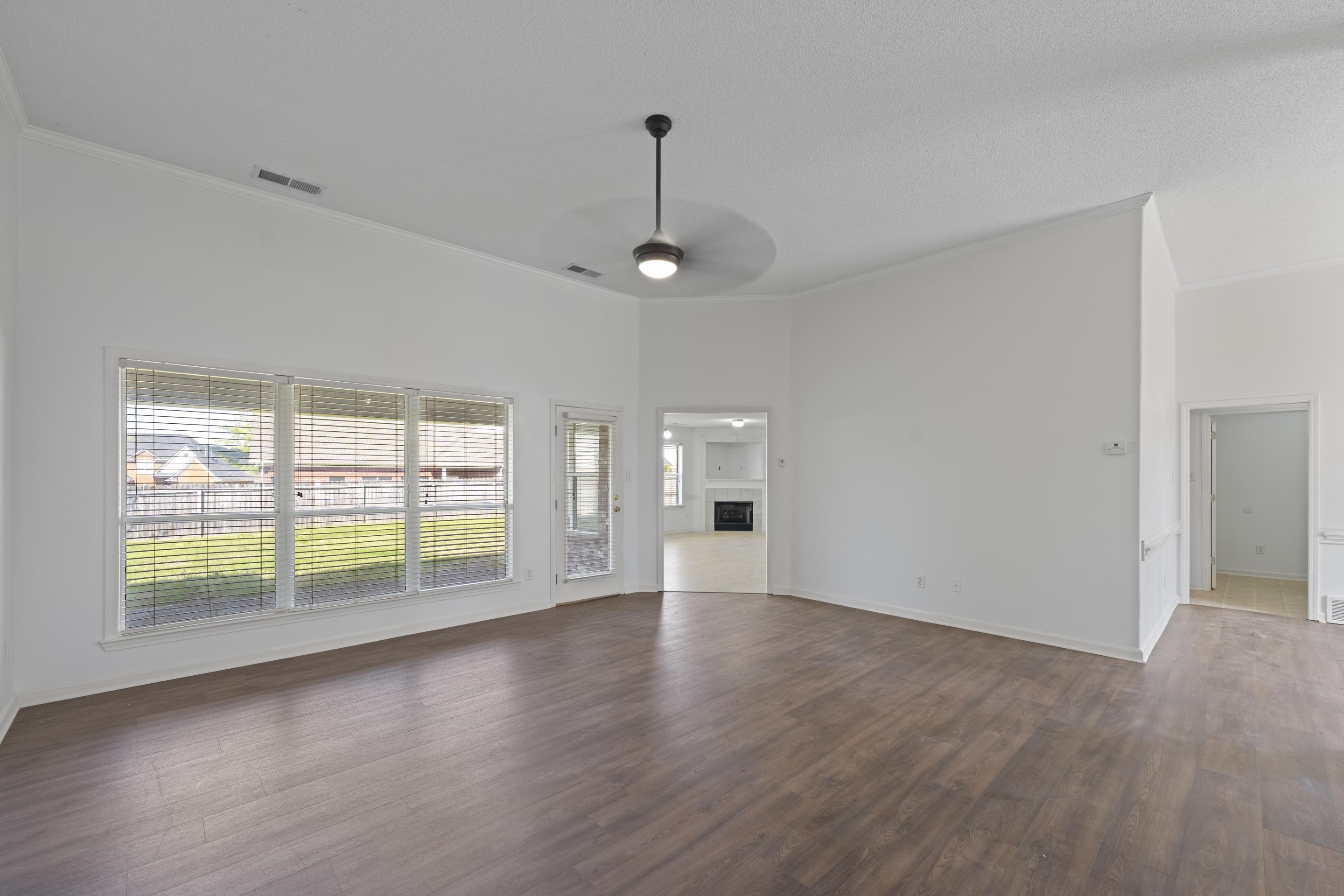 1104 Macon Hall Road Cordova, TN 38018 - Photo 6 of 34 Unfurnished living room featuring ornamental molding, a ceiling fan, visible vents, and dark wood-style flooring