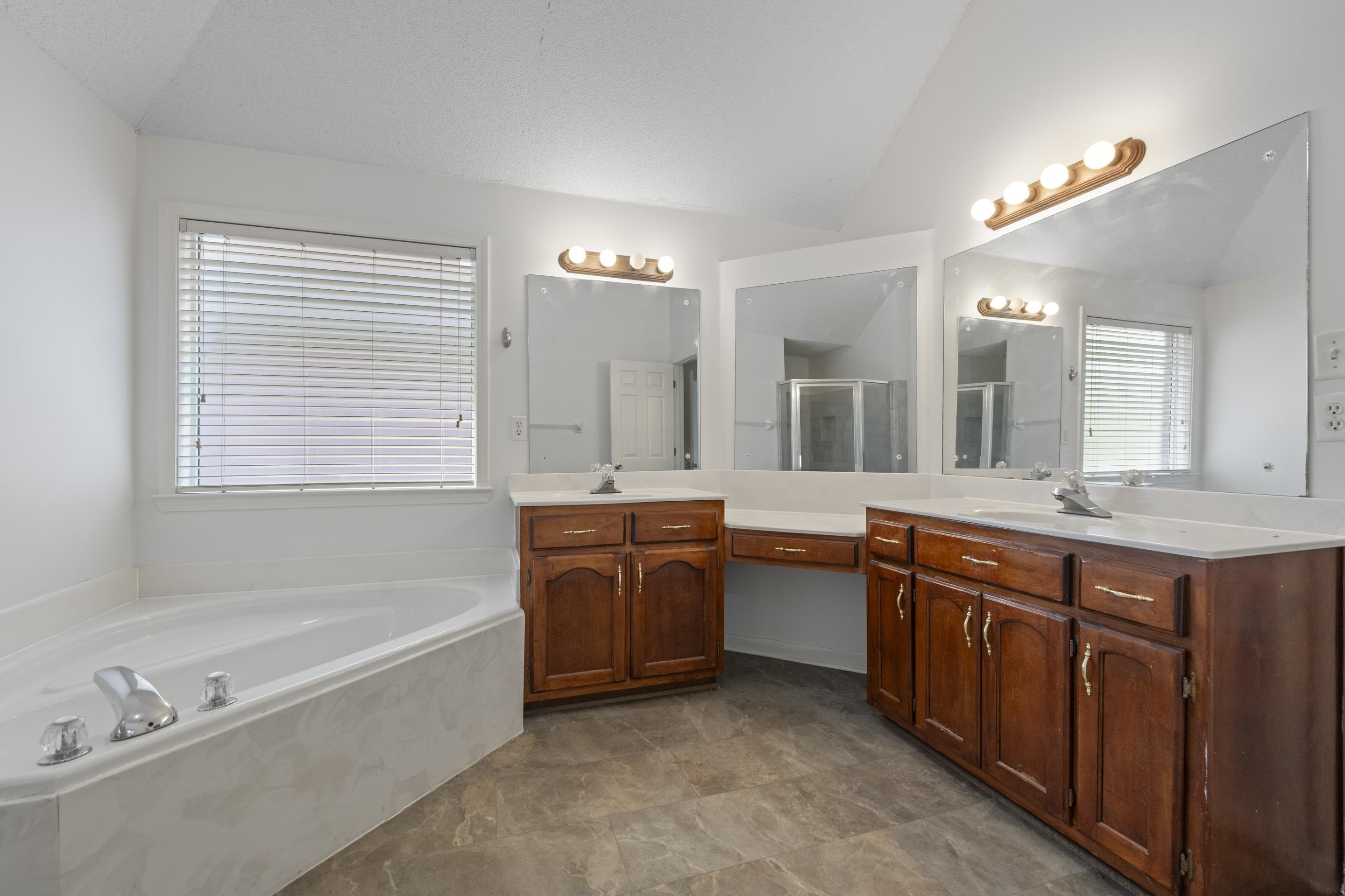 1104 Macon Hall Road Cordova, TN 38018 - Photo 9 of 34 Bathroom featuring two vanities, a sink, a shower stall, lofted ceiling, and a garden tub