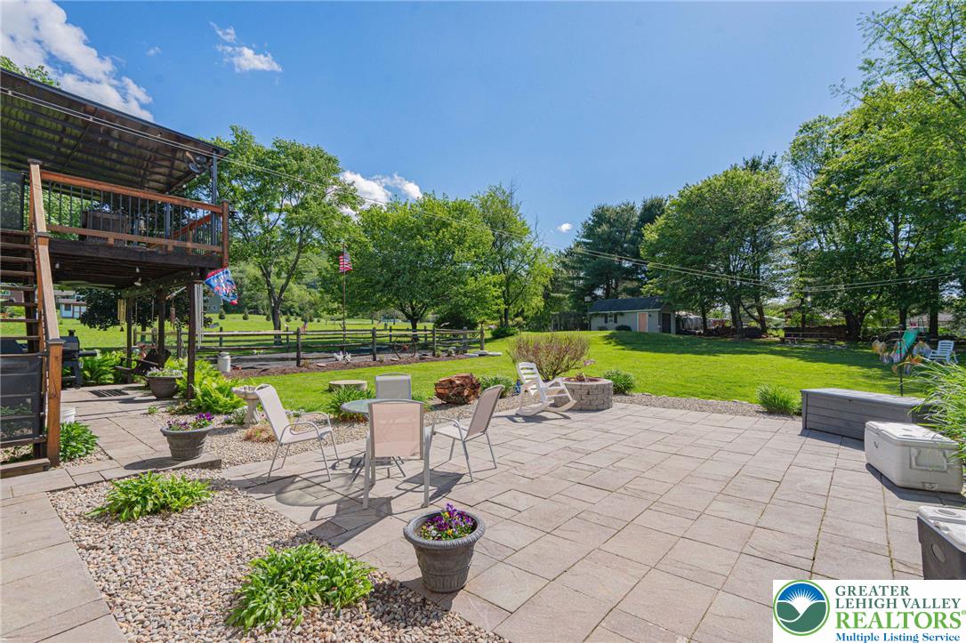 341 Lower Greenhill Road Kunkletown, PA 18058 - Photo 53 of 69 An inviting stone patio unfolds into a generous green yard, offering abundant space for outdoor enjoyment.