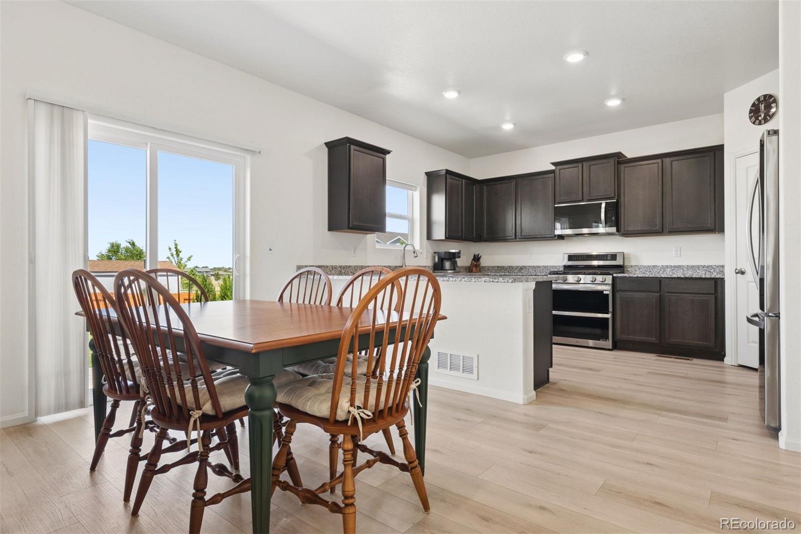 7307 Animas Avenue Frederick, CO 80530 - Photo 16 of 49 a kitchen with stainless steel appliances granite countertop a stove top oven a sink dishwasher a dining table and chairs