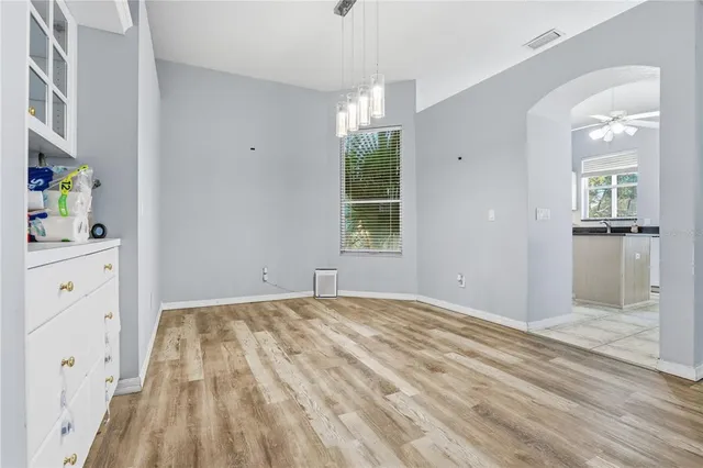 a view of empty room with wooden floor and fan