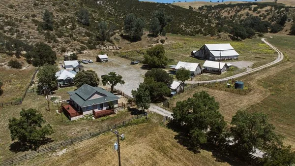 an aerial view of a house with a yard lake and mountain view in back