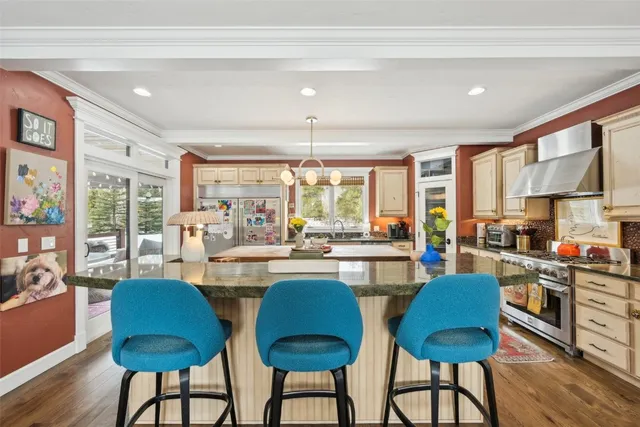 a kitchen with stainless steel appliances granite countertop table chairs stove and wooden cabinets