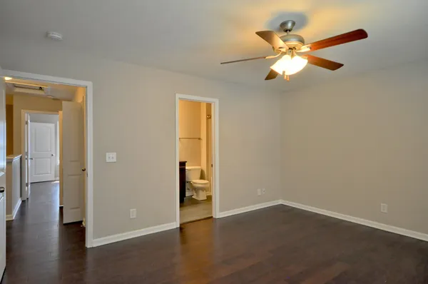 an empty room with wooden floor closet and windows