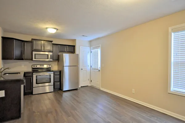 a kitchen with granite countertop wooden floors stainless steel appliances and window