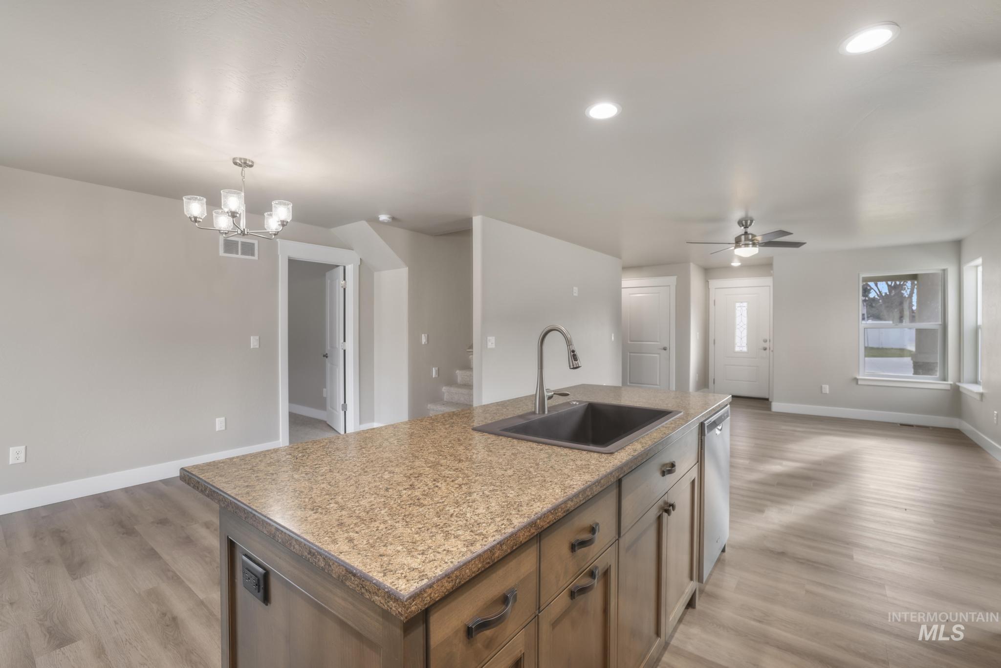 812 Jack Avenue Jerome, ID 83338 - Photo 38 of 38 Kitchen with open floor plan, a center island with sink, light wood-style flooring, brown cabinets, and decorative light fixtures