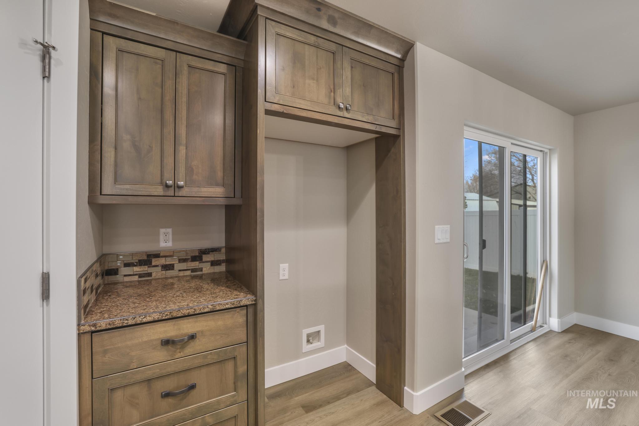 812 Jack Avenue Jerome, ID 83338 - Photo 10 of 38 Kitchen with dark stone counters, light wood finished floors, tasteful backsplash, and brown cabinetry