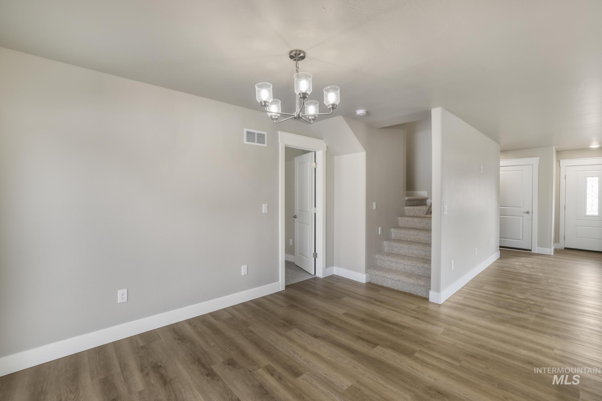 812 Jack Avenue Jerome, ID 83338 - Photo 11 of 38 Unfurnished dining area featuring a chandelier, wood finished floors, and stairway