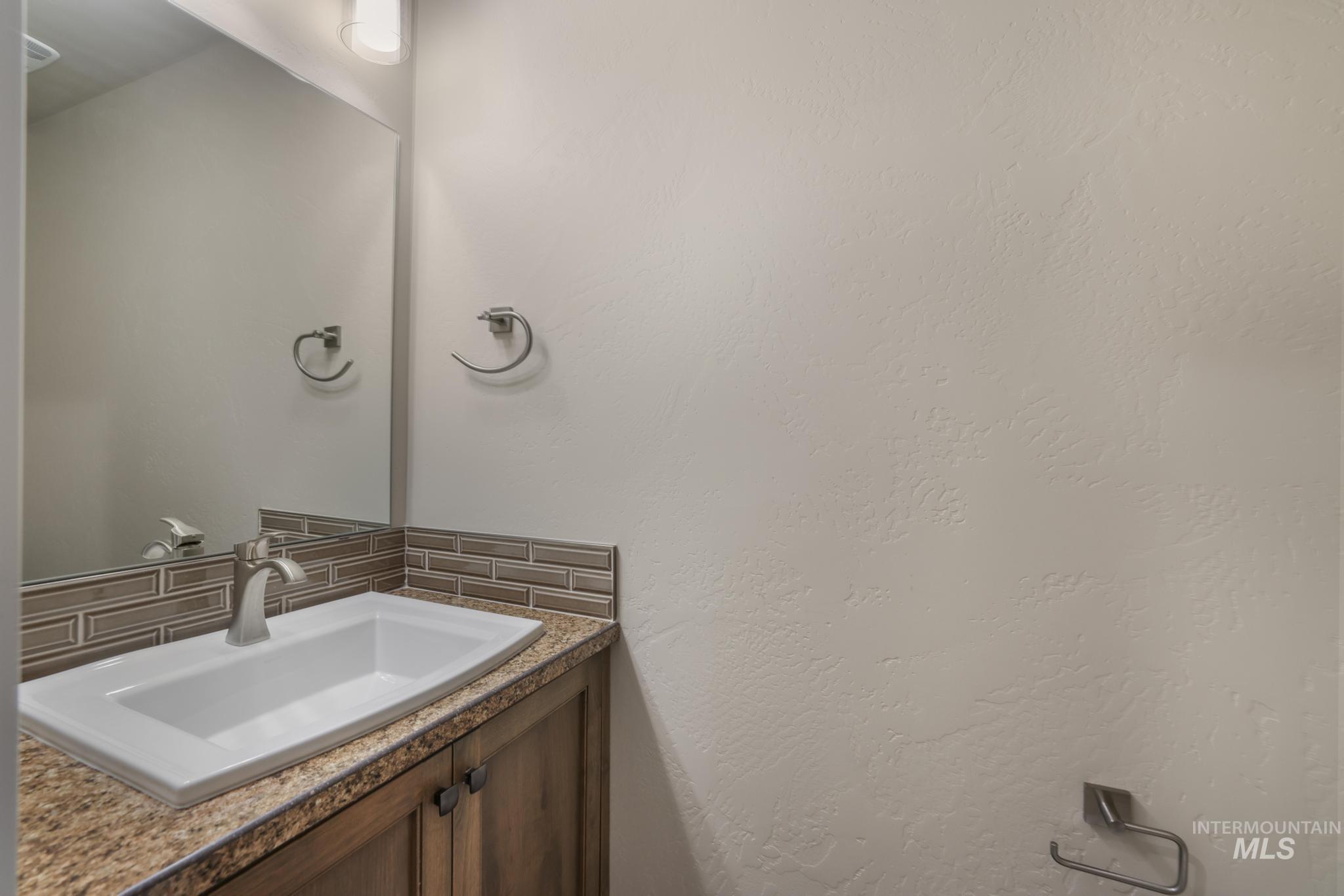 812 Jack Avenue Jerome, ID 83338 - Photo 12 of 38 Bathroom with decorative backsplash, vanity, and a textured wall