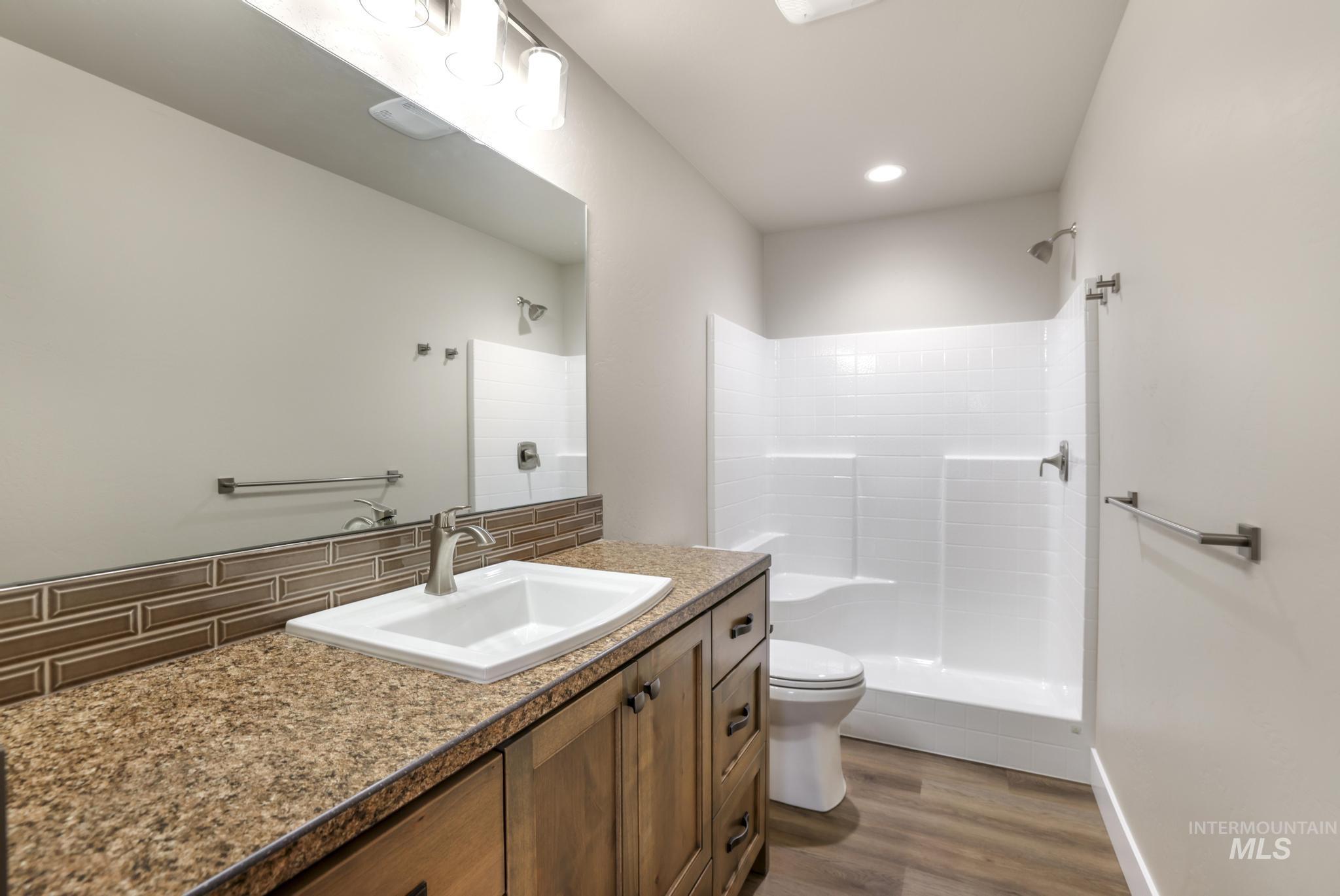 812 Jack Avenue Jerome, ID 83338 - Photo 16 of 38 Bathroom featuring vanity, a shower stall, dark wood-style flooring, and decorative backsplash