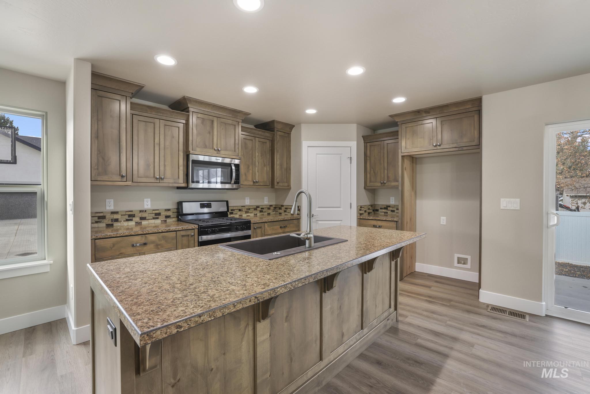 812 Jack Avenue Jerome, ID 83338 - Photo 7 of 38 Kitchen featuring healthy amount of natural light, appliances with stainless steel finishes, a kitchen island with sink, recessed lighting, and a breakfast bar area