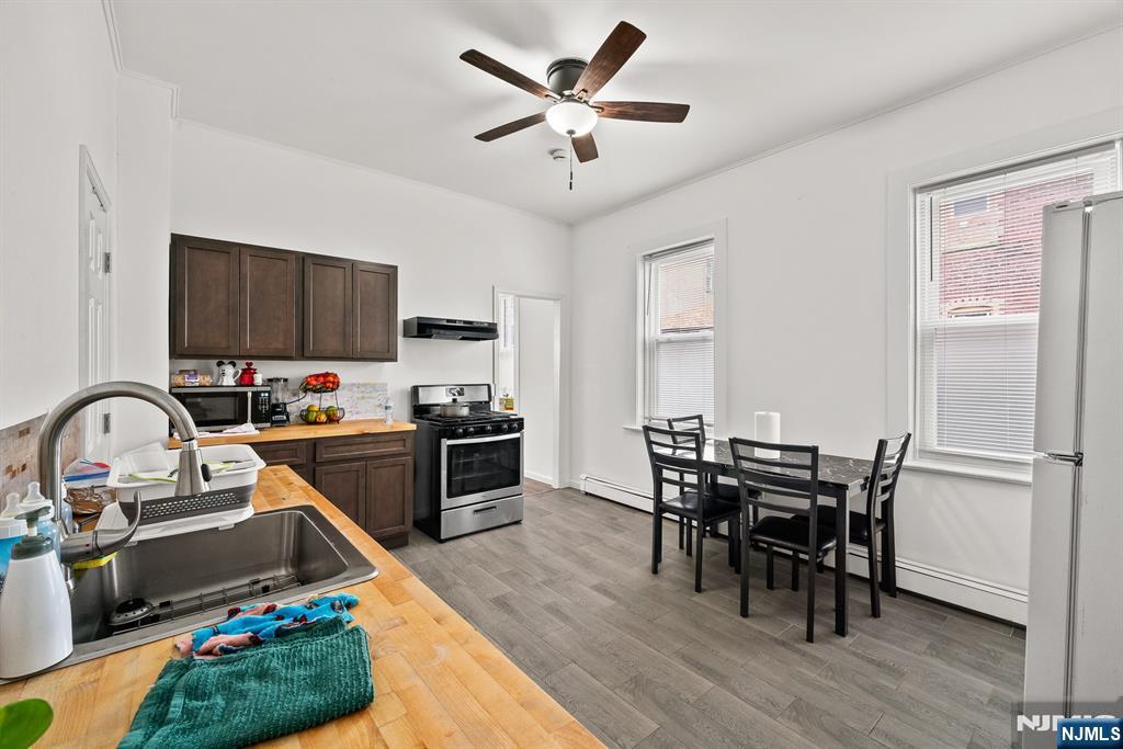 94 Center Street Clifton, NJ 07011 - Photo 13 of 38 a kitchen with stainless steel appliances granite countertop a stove top oven a sink dishwasher a dining table and chairs with wooden floor