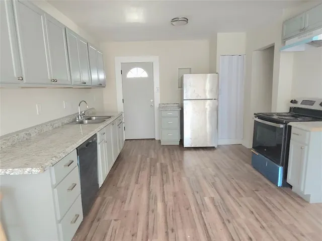 a kitchen with a sink a refrigerator a stove and cabinets with wooden floor