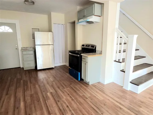 a kitchen with a refrigerator and wooden floor