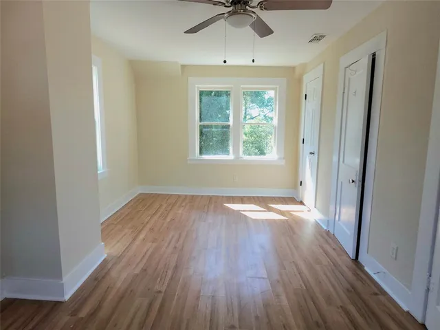 an empty room with wooden floor and windows