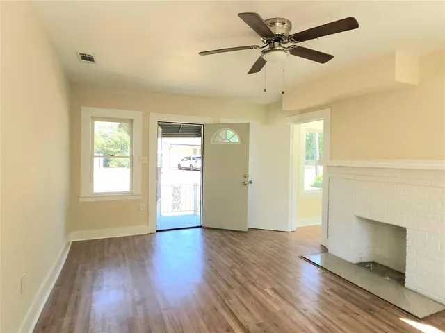 a view of an empty room with window and wooden floor