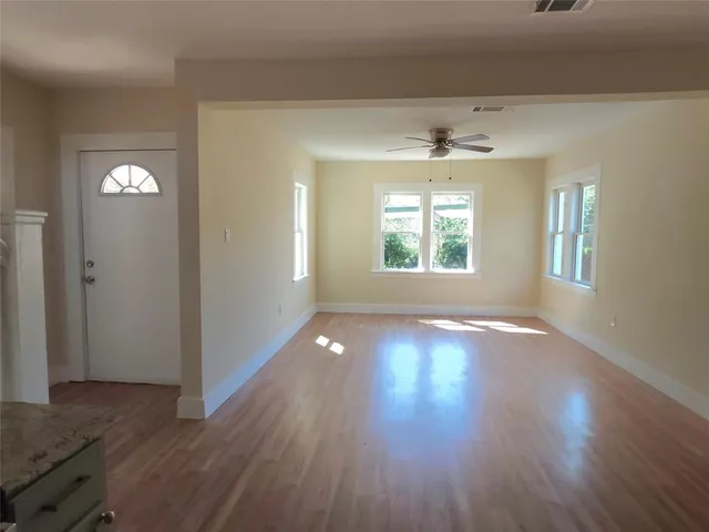 an empty room with wooden floor and windows