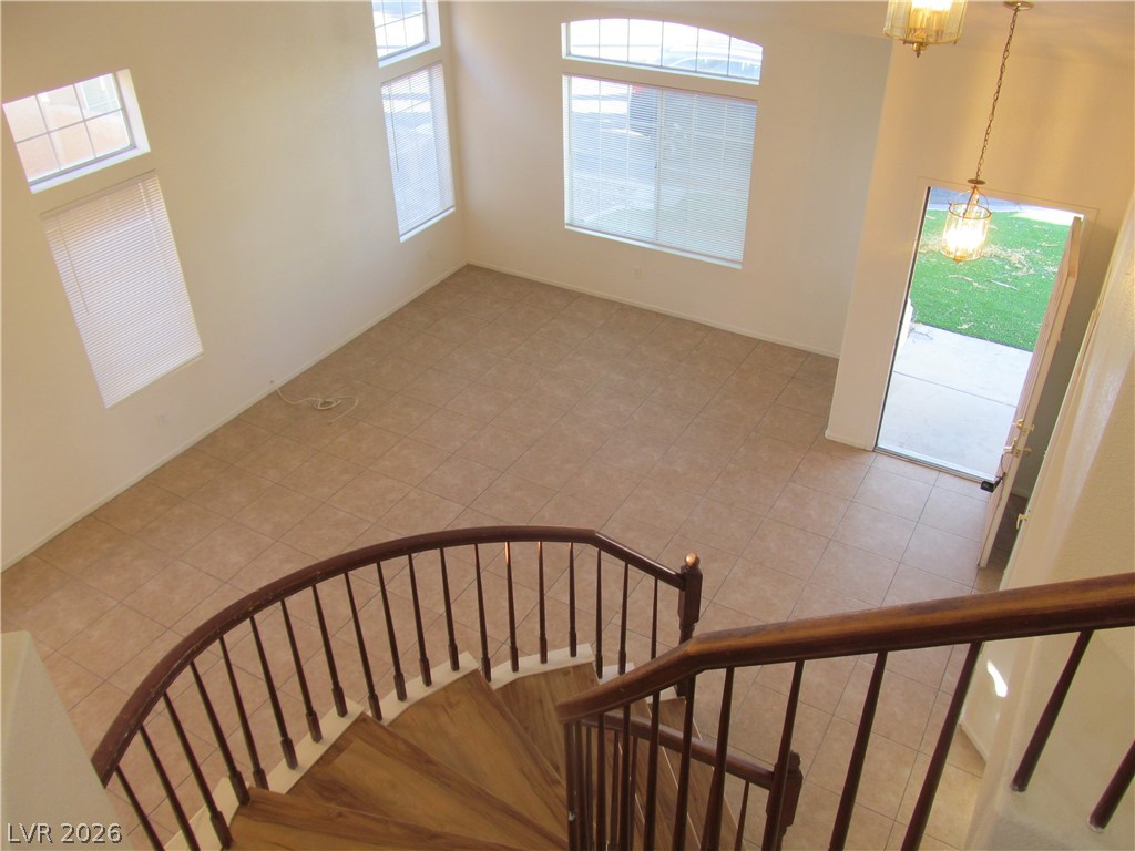 8701 Crescent Ridge Lane Las Vegas, NV 89134 - Photo 5 of 28 A graceful curved staircase descends to an airy room with high ceilings and tiled floors.