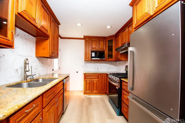 a kitchen with stainless steel appliances granite countertop sink stove and refrigerator