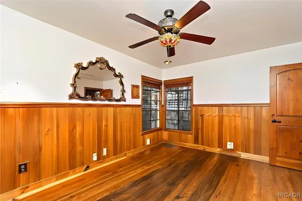 an empty room with wooden floor closet and windows