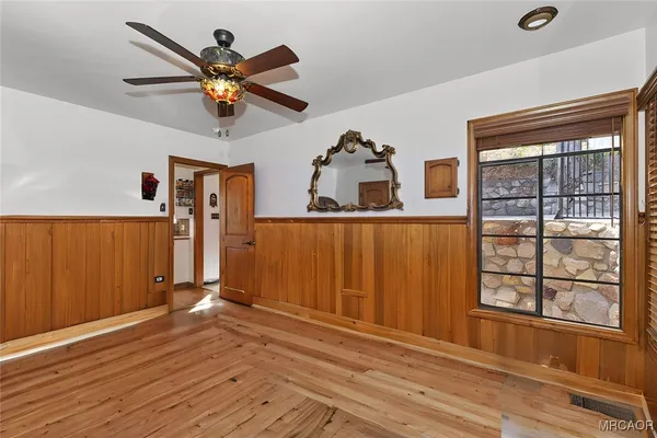 an empty room with wooden floor closet fan and windows