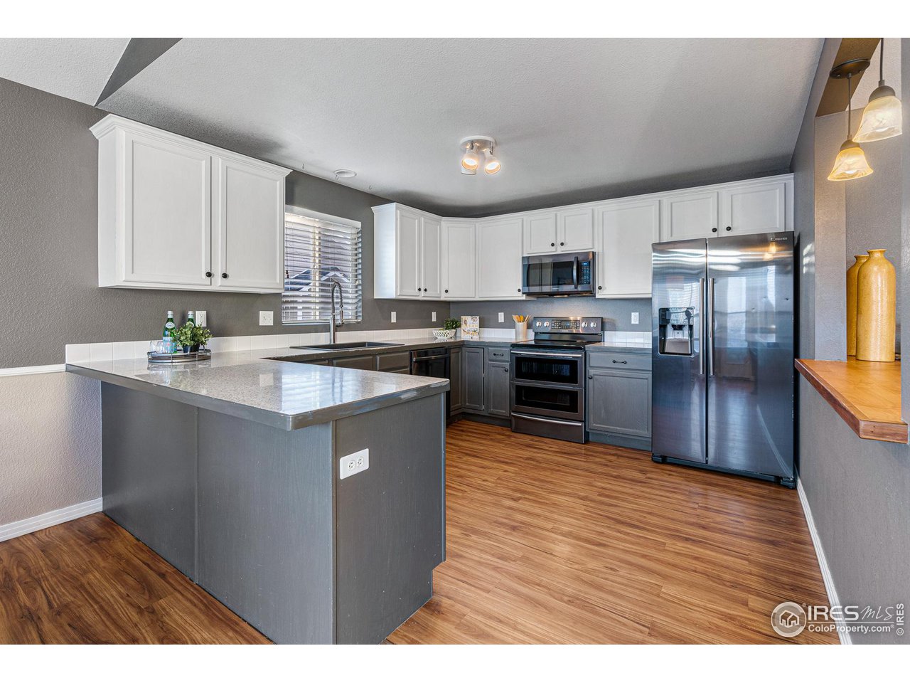 628 Sumac Street Frederick, CO 80530 - Photo 15 of 38 a kitchen with stainless steel appliances granite countertop a refrigerator a sink dishwasher a stove top oven a kitchen island and chairs with wooden floor