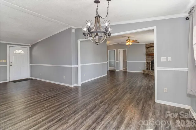 a view of a livingroom with wooden floor a ceiling fan and windows