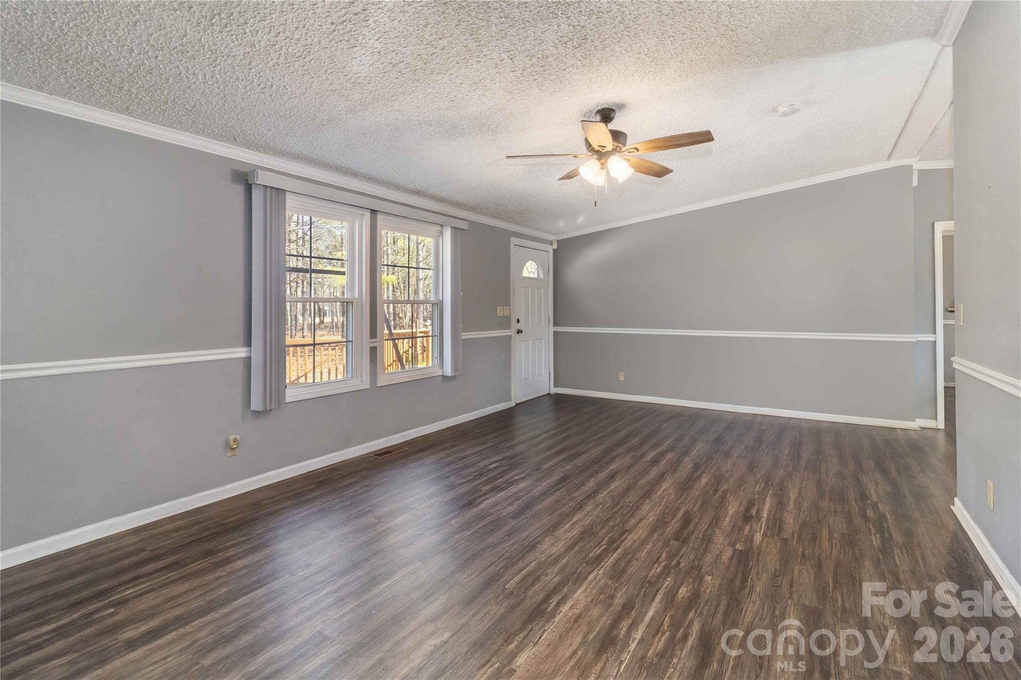 482 Pine Road Jefferson, SC 29718 - Photo 7 of 39 an empty room with wooden floor chandelier fan and windows